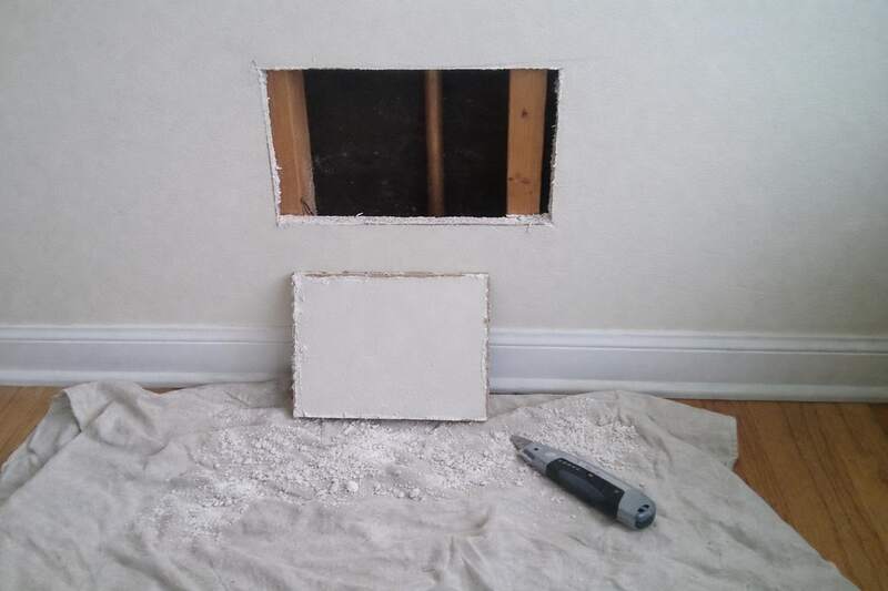 An access hole cut between two studs in an interior wall