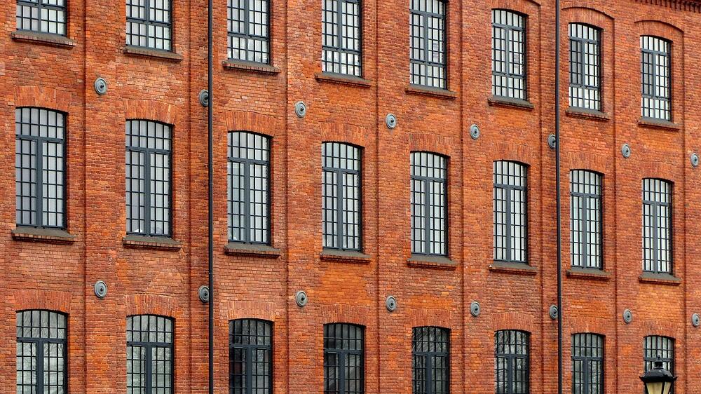 The brick wall and tall industrial windows of a former factory converted to lofts