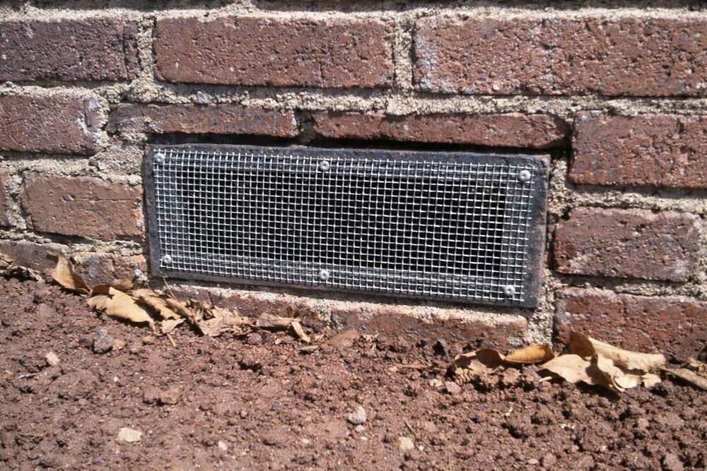 Galvanized hardware cloth cut and fastened tight over a foundation vent in a red brick wall